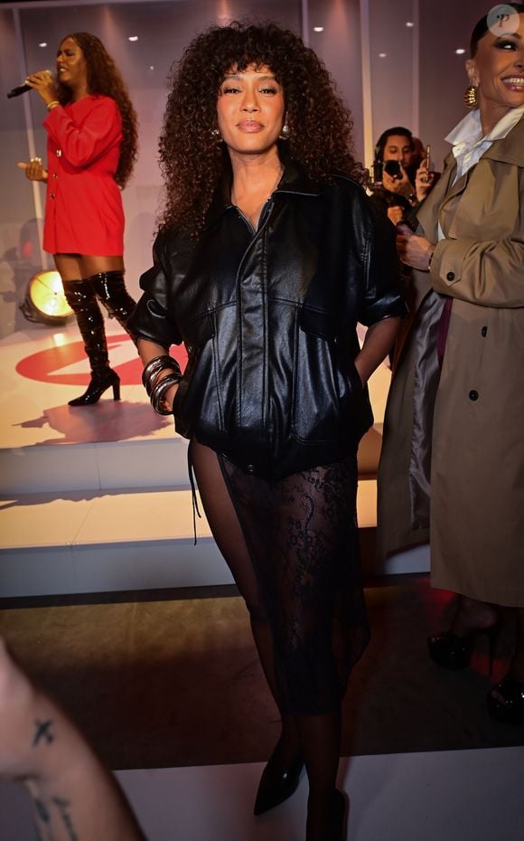 Taís Araujo surge elegante com jaqueta de couro volumosa e saia midi de renda preta durante desfile de moda na capital paulista