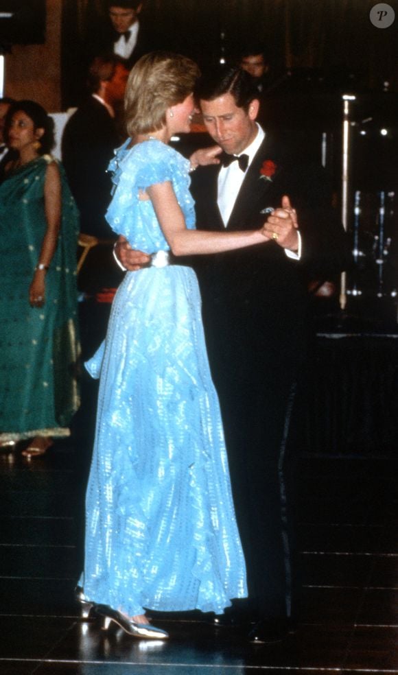O Príncipe Charles e Diana, Princesa de Gales, dançam durante um jantar de gala no Hotel Wentworth, em Sydney, em 28 de março de 1983. Ela veste um modelo azul-claro com cinto prateado, assinado por Bruce Oldfield e o metalizado foi o toque de luz constante nos pés da princesa