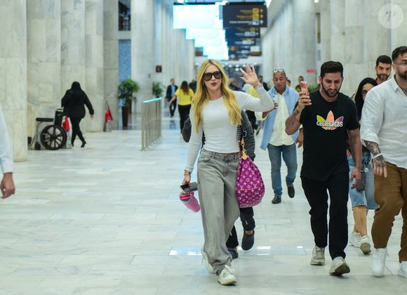 Virgínia apostou em uma composição urbana e confortável para viajar: blusa branca ajustada, jeans estonado wide leg e tênis esportivo chunky