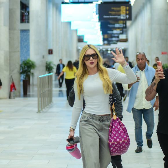 Virgínia apostou em uma composição urbana e confortável para viajar: blusa branca ajustada, jeans estonado wide leg e tênis esportivo chunky