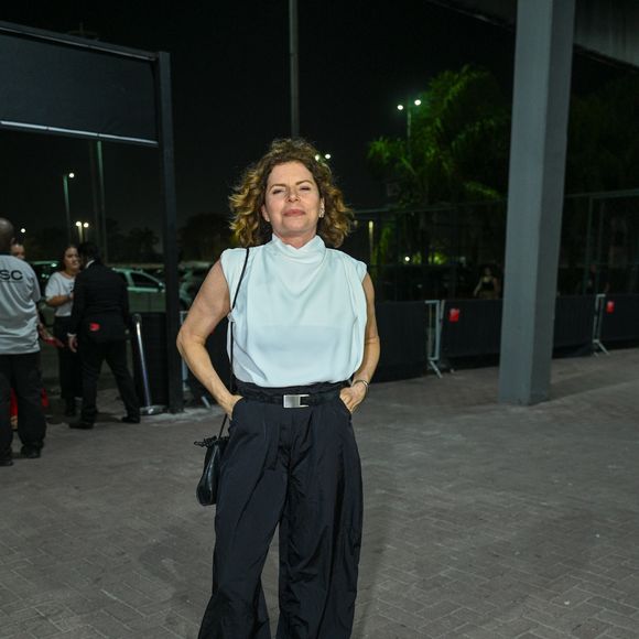 Débora Bloch vestiu uma blusa branca de gola alta sem mangas com caimento levemente drapeado no peito. Ela combinou a peça superior com uma calça jogger preta de cintura alta com cinto e ajuste na barra no estilo streetwear. Para fechar o look moderno e confortável, a atriz usou tênis esportivos robustos e uma bolsa tiracolo preta