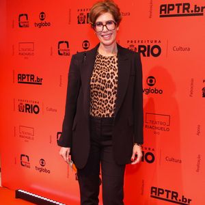 Maria Clara Gueiros: A atriz usa um terno preto clássico de corte reto estruturado sobre uma blusa de gola redonda com estampa de oncinha. O visual sóbrio e moderno é arrematado por óculos de armação escura marcante, unhas vermelhas e botas pretas de cano curto e salto fino