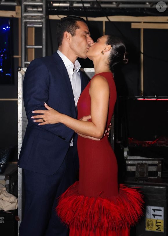 Marcus Buaiz combina traje de alfaiataria azul-marinho com camisa social branca sem gravata; casal dá beijão em frente aos fotógrafos