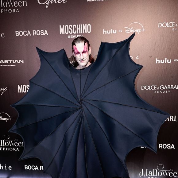 Dudu Bertholini veste uma criação dramática e conceitual em tom azul-marinho, inspirada na silhueta de asas de morcego ou guarda-chuva estruturado. O traje destaca-se por uma imponente peça frontal pregueada e pontiaguda com varetas estruturadas que se abrem como um leque à frente do corpo