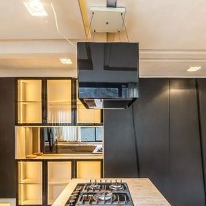 Fogão industrial, chão verde e armários pretos compõem o cômodo
